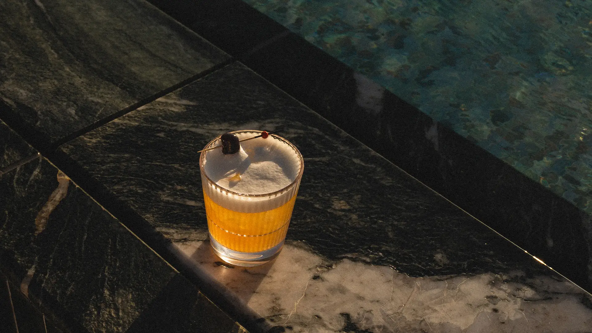 Elegant cocktail ved poolkanten på ROX Resort i varmt aftenslys.