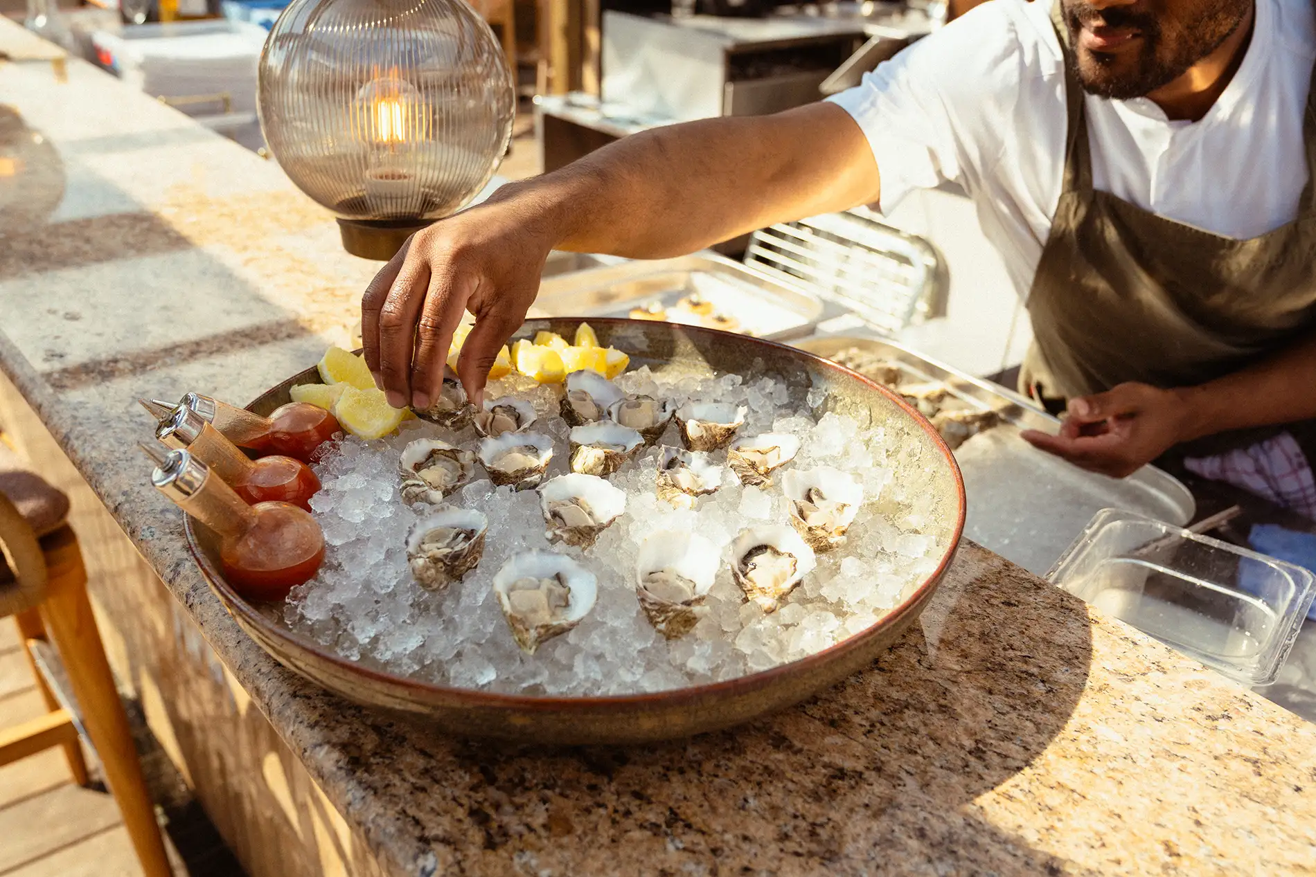 Oysters plated on a big plate of ice, along with tabasco sauce and lemons.